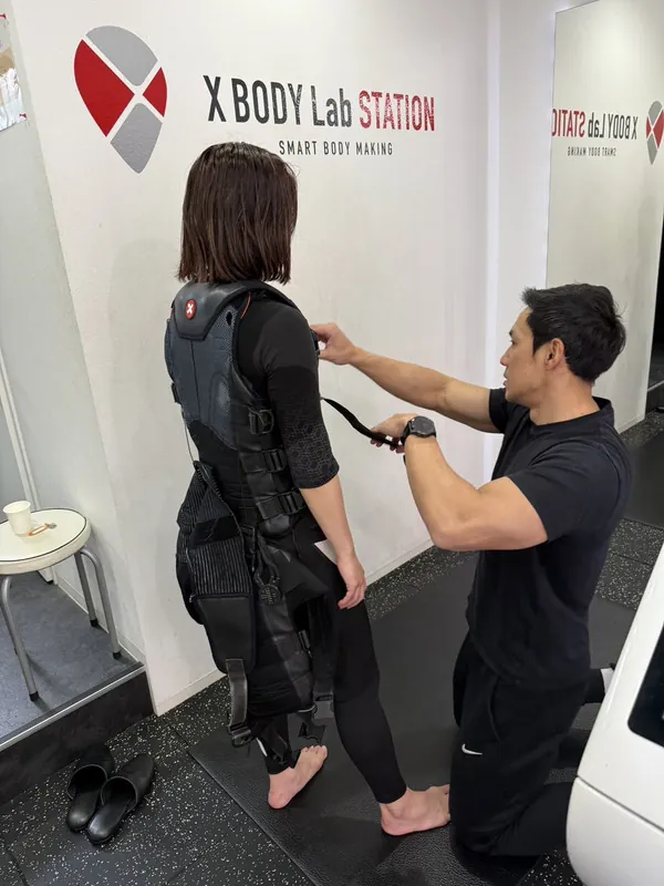 トレーニング風景1:トレーナーがX BODY専用スーツの装着をサポートする様子